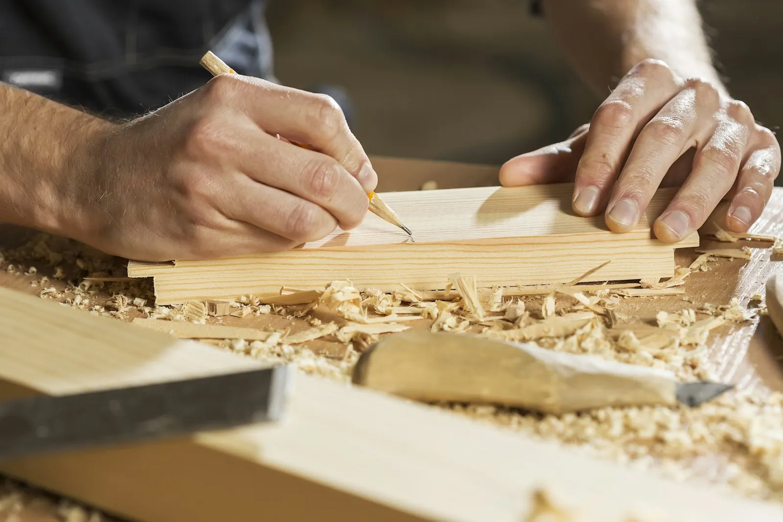 A tradesperson marking a measurement on a timber board with a pencil