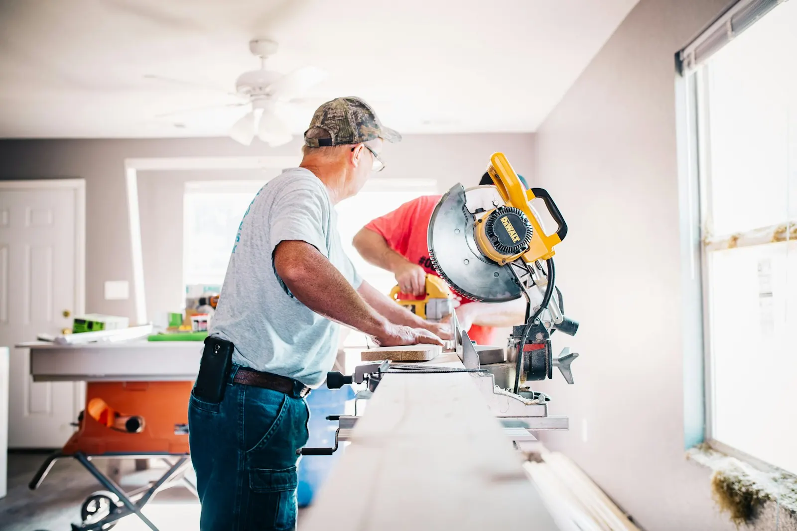 A builder cutting timber with a mitre saw inside a house