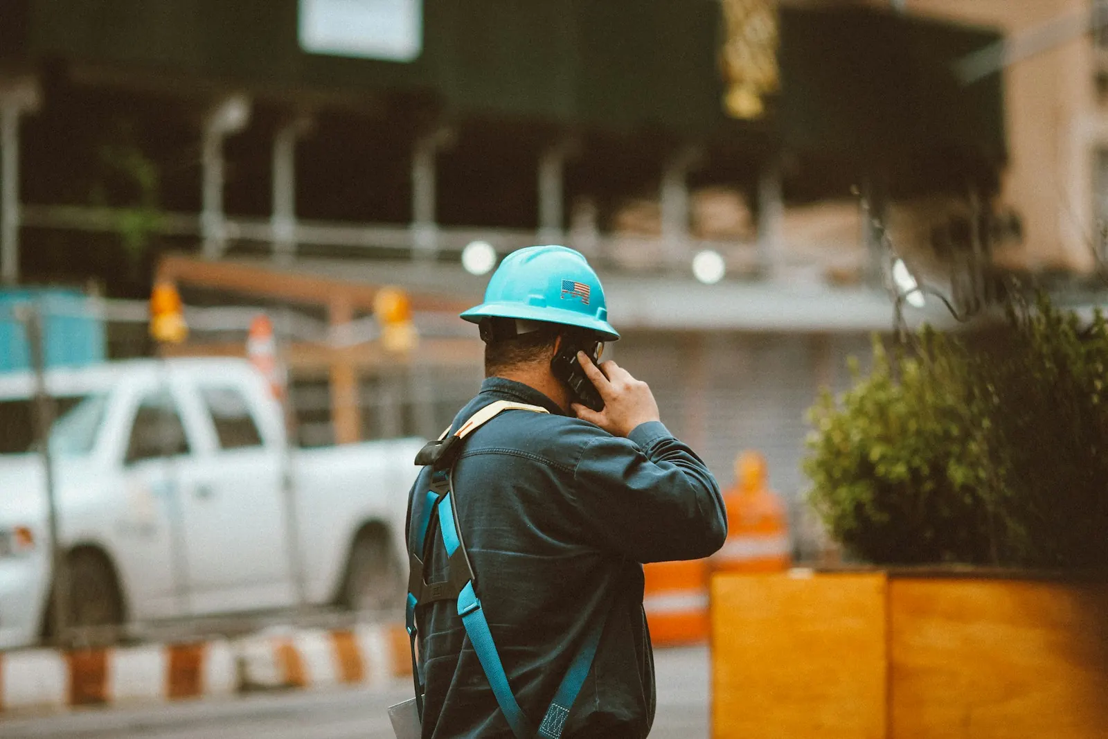 A tradesperson in a hard hat talking on the phone on a job site