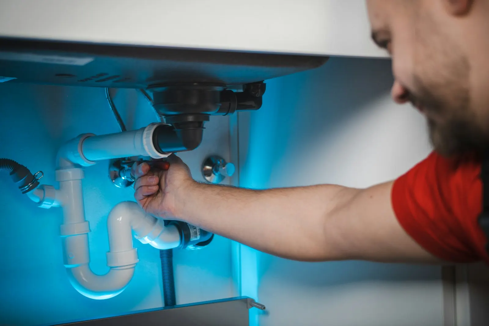 A plumber fitting pipes under a sink