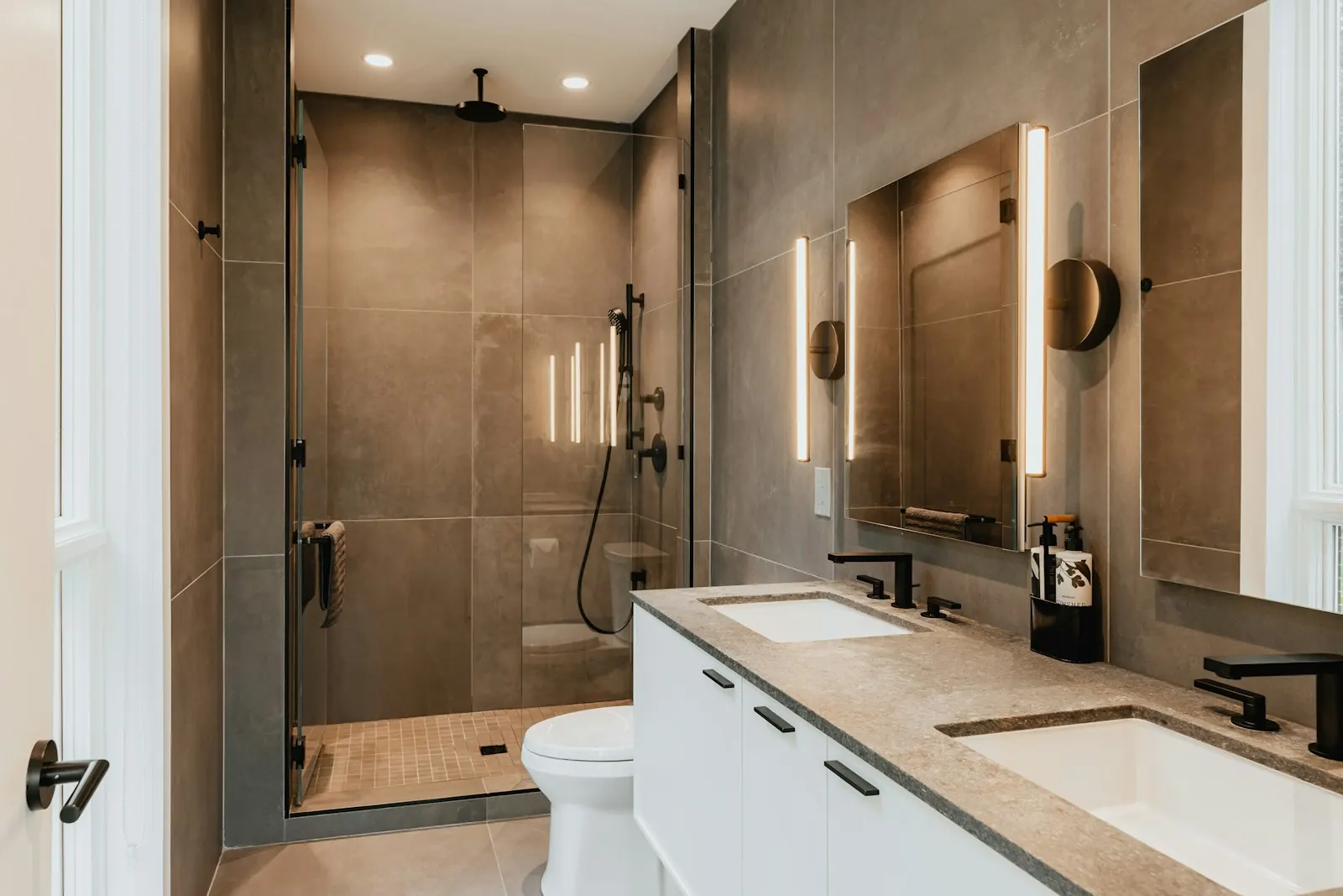 A finished modern bathroom with a walk-in shower and vanity