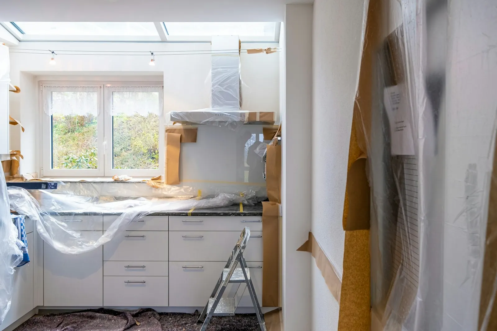 A kitchen part-way through renovation with the cabinets covered in plastic