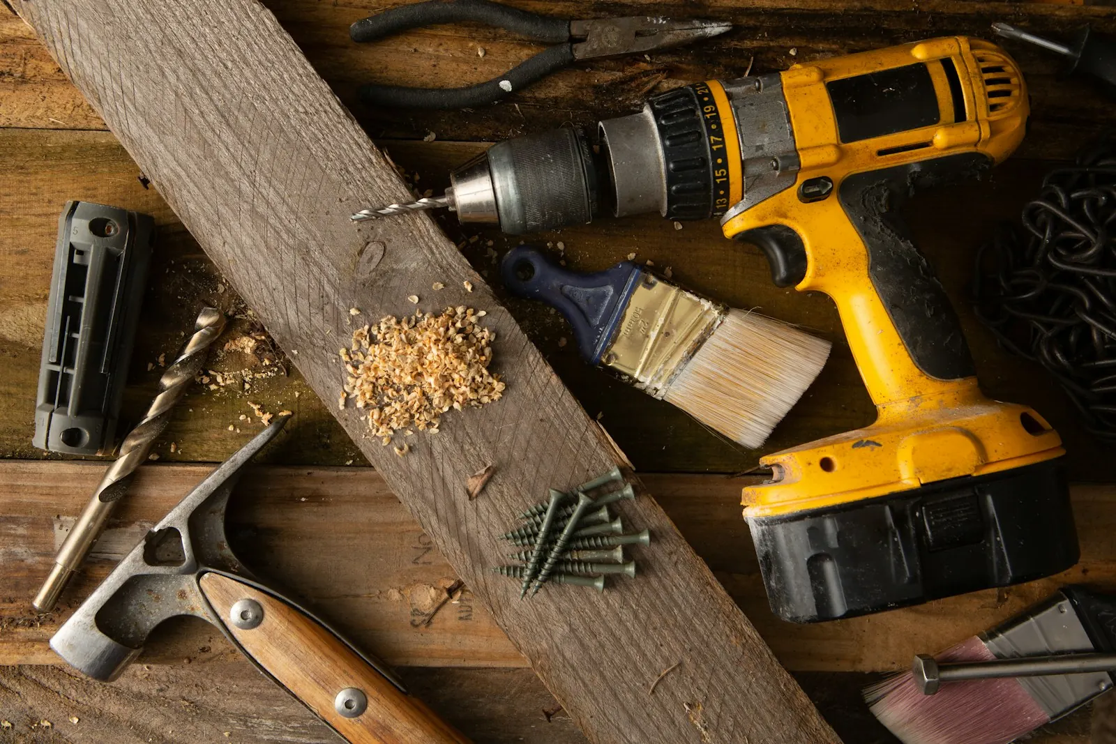A cordless drill and hand tools on a timber workbench