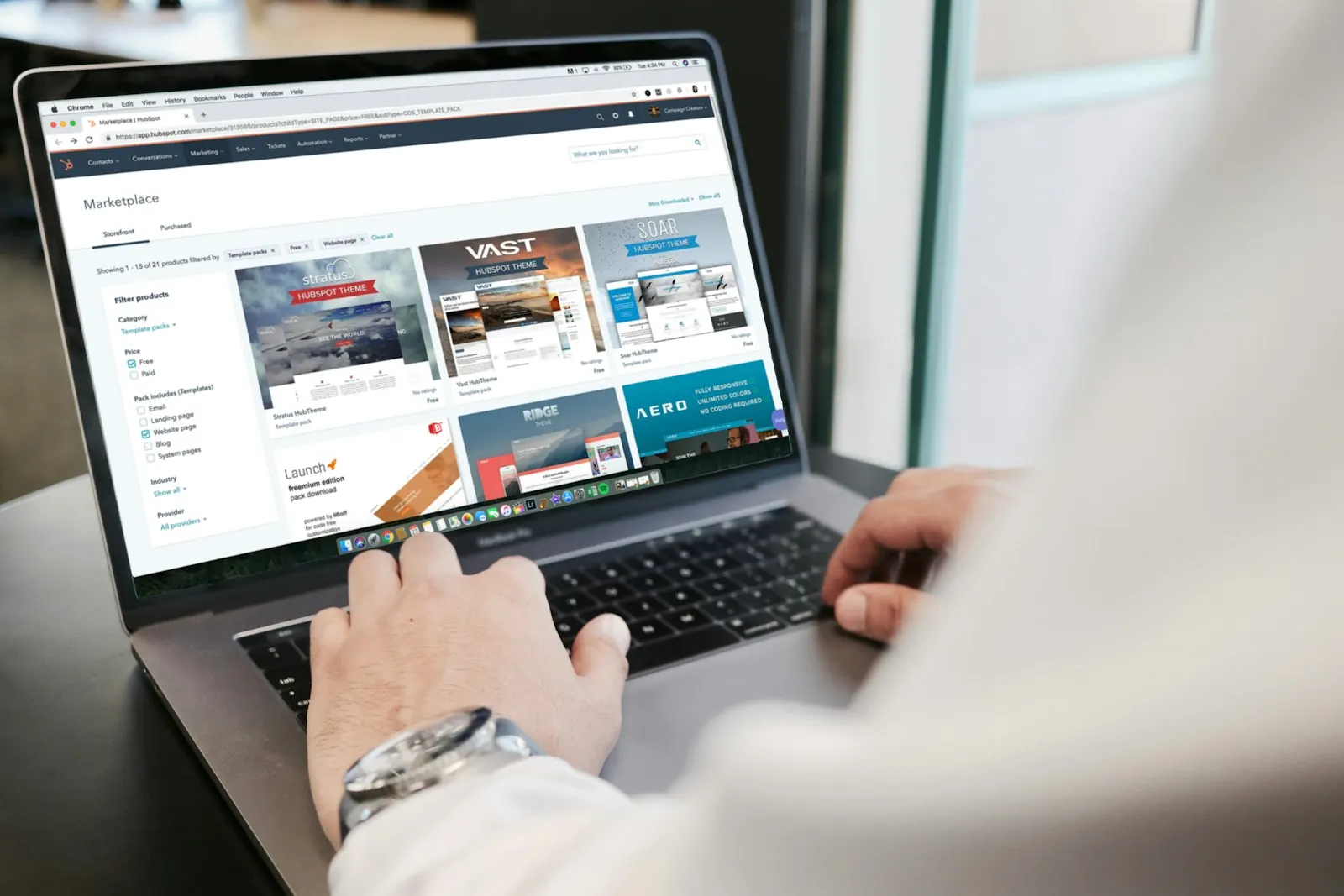 Hands typing on a laptop showing a website builder